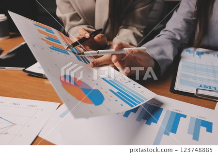 Group of confident business people point to graphs and charts to analyze market data, balance sheet, account, net profit to plan new sales strategies to increase production capacity. 123748885