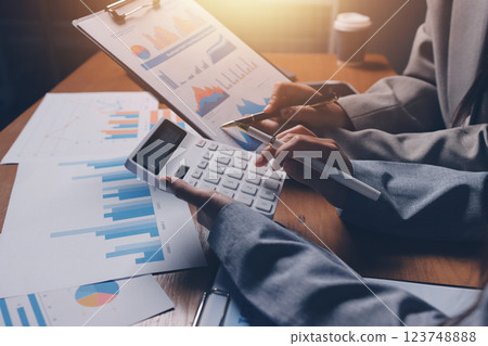 Group of confident business people point to graphs and charts to analyze market data, balance sheet, account, net profit to plan new sales strategies to increase production capacity. 123748888