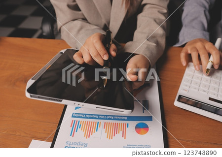 Group of confident business people point to graphs and charts to analyze market data, balance sheet, account, net profit to plan new sales strategies to increase production capacity. Group of confident business people point to graphs and charts to analyze market data, balance sheet, account, net profit to plan new sales strategies to increase production capacity. 123748890