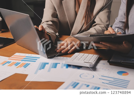 Group of confident business people point to graphs and charts to analyze market data, balance sheet, account, net profit to plan new sales strategies to increase production capacity. 123748894