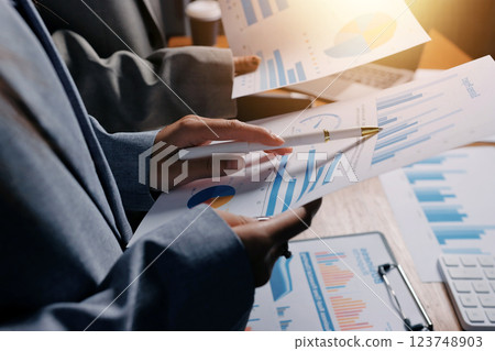 Group of confident business people point to graphs and charts to analyze market data, balance sheet, account, net profit to plan new sales strategies to increase production capacity. 123748903