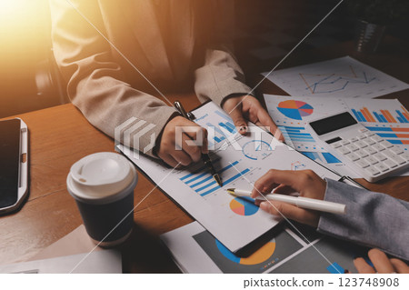 Group of confident business people point to graphs and charts to analyze market data, balance sheet, account, net profit to plan new sales strategies to increase production capacity. 123748908