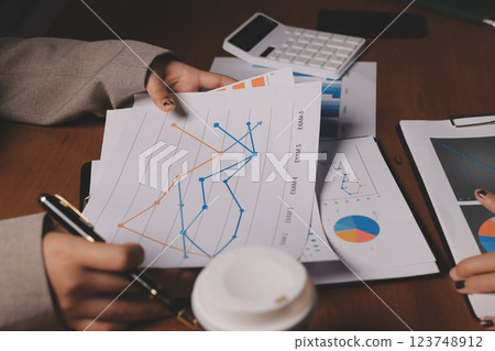Group of confident business people point to graphs and charts to analyze market data, balance sheet, account, net profit to plan new sales strategies to increase production capacity. Group of confident business people point to graphs and charts to analyze market data, balance sheet, account, net profit to plan new sales strategies to increase production capacity. 123748912