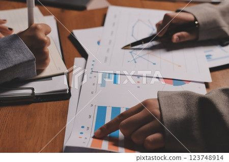 Group of confident business people point to graphs and charts to analyze market data, balance sheet, account, net profit to plan new sales strategies to increase production capacity. Group of confident business people point to graphs and charts to analyze market data, balance sheet, account, net profit to plan new sales strategies to increase production capacity. 123748914