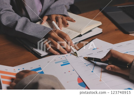 Group of confident business people point to graphs and charts to analyze market data, balance sheet, account, net profit to plan new sales strategies to increase production capacity. Group of confident business people point to graphs and charts to analyze market data, balance sheet, account, net profit to plan new sales strategies to increase production capacity. 123748915