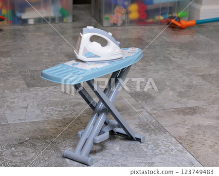 Toy household appliances, iron, ironing table at home on floor. Cleaning, household chores, baby and educational games. Toy household appliances, iron, ironing table at home on floor. Cleaning, household chores, baby and educational games. 123749483