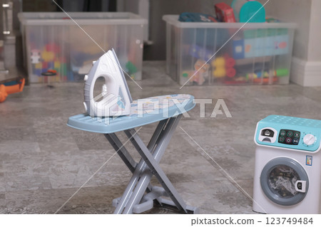 Toy household appliances, iron, ironing table, washing machine at home on floor. Cleaning, household chores, baby and educational games. Toy household appliances, iron, ironing table, washing machine at home on floor. Cleaning, household chores, baby and educational games. 123749484