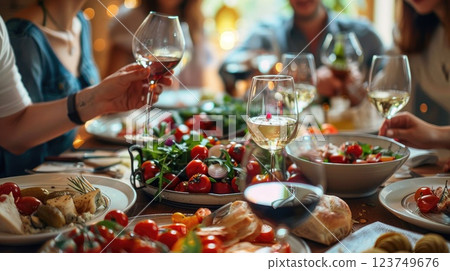 A group of people are gathered around a table with a variety of food and drinks 123749676