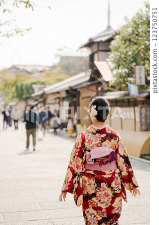 A woman in a kimono walking down the street A woman in a kimono walking down the street 123750751
