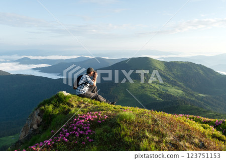 Photographer sitting on a blooming mountain ridge 123751153
