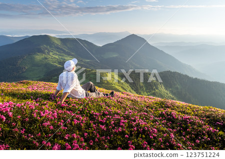 Traveler sitting among blooming rhododendrons Traveler sitting among blooming rhododendrons 123751224