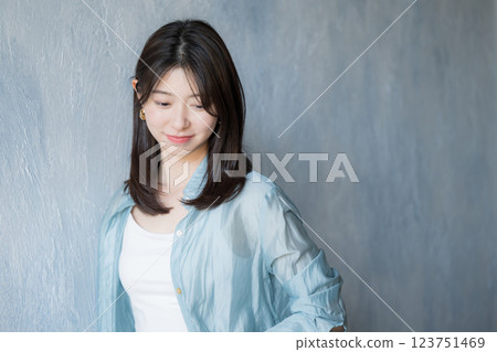 一位身著休閒服裝的女士在淺藍色背景中微笑並低頭 123751469