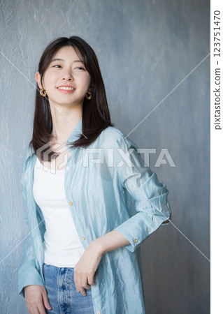 穿著休閒服裝的女人微笑著,仰望淡藍色背景 穿著休閒服裝的女人微笑著,仰望淡藍色背景 123751470