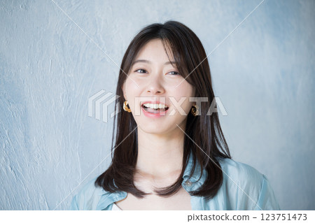 Woman in casual clothes smiling and looking up against light blue background, looking at camera 123751473