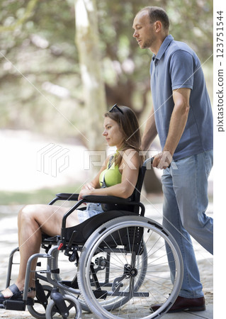 Nurse pushing patient in wheelchair in park during sunny day 123751544