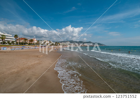 Beautiful sandy beach with gentle ocean waves and mountain view in Sitges, Spain 123751552
