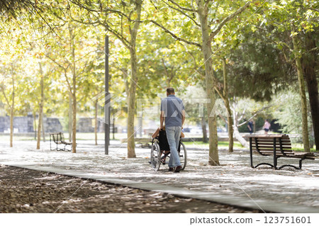 Man pushing senior woman in wheelchair in a sunny park Man pushing senior woman in wheelchair in a sunny park 123751601