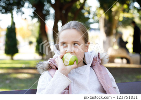 Kid holding green apple. Young girl in park, outdoors portrait 123751811