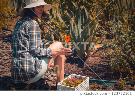 A woman cultivates plants on a sunny day. 123752161
