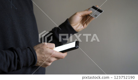 Man holds bank card and mobile phone in his hands. 123752190
