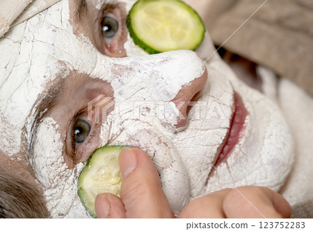 Old woman applies a white mask on her face. 123752283