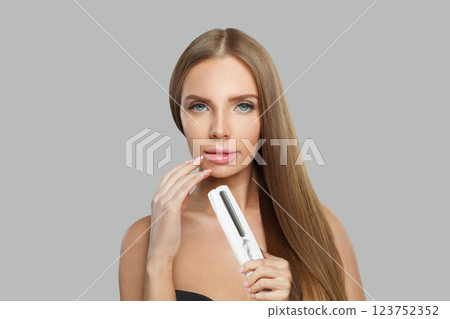 Beautiful fashion model woman using hair straighteners iron on white background. Harstyle, hair care Beautiful fashion model woman using hair straighteners iron on white background. Harstyle, hair care 123752352