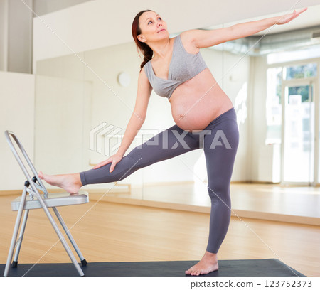 Pregnant woman is engaged in yoga. Chair exercises 123752373