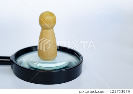 A wooden doll standing on magnifying glass. Representing the chosen one or leadership concept A wooden doll standing on magnifying glass. Representing the chosen one or leadership concept 123753979
