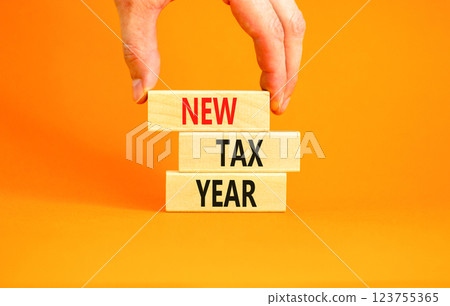 New tax year symbol. Concept words New tax year on beautiful wooden blocks. Beautiful orange background. Businessman hand. Business new tax year concept. Copy space. New tax year symbol. Concept words New tax year on beautiful wooden blocks. Beautiful orange background. Businessman hand. Business new tax year concept. Copy space. 123755365
