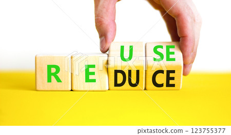 Reuse or reduce symbol. Concept words Reuse Reduce on wooden block. Beautiful yellow table white background. Businessman hand. Business reuse or reduce concept. Copy space. Reuse or reduce symbol. Concept words Reuse Reduce on wooden block. Beautiful yellow table white background. Businessman hand. Business reuse or reduce concept. Copy space. 123755377