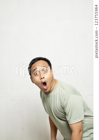 Funny face man wow and OMG. Shocked and surprised face of an Asian man in a sage green shirt isolated on white. 123755964