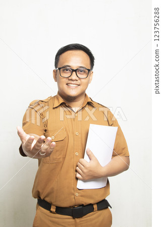 Confident smile Teacher dressed in old khaki and carrying a book on his chest, Indonesian Teacher Profile Concept isolated on white background 123756288