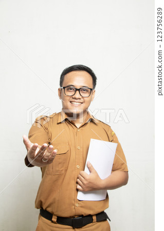 Confident smile Teacher dressed in old khaki and carrying a book on his chest 123756289