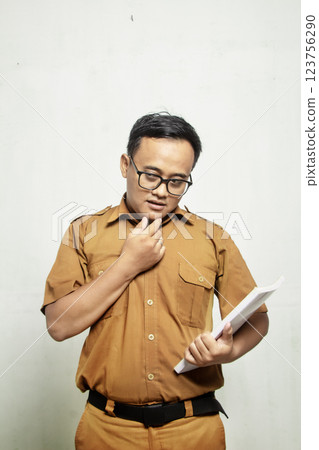 wise asian indonesian teacher standing holding book isolated on white background with khaki shirt 123756290