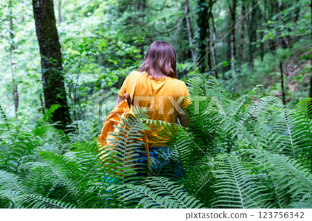 young woman wearing yellow backpack and T-shirt exploring lush green forest with dense ferns,enjoying nature while hiking in scenic woodland,wilderness exploration, forest therapy, active lifestyles young woman wearing yellow backpack and T-shirt exploring lush green forest with dense ferns,enjoying nature while hiking in scenic woodland,wilderness exploration, forest therapy, active lifestyles 123756342