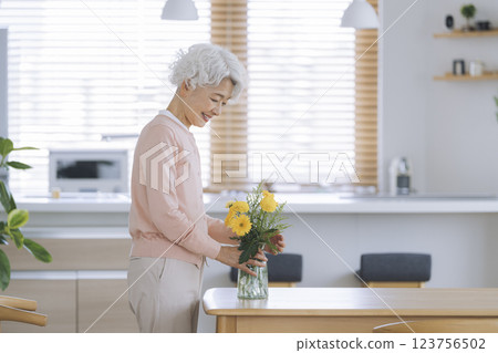 Senior woman decorating the dining table at home with flowers 123756502
