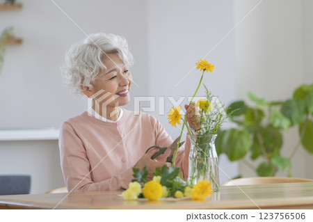 Senior woman arranging flowers at home 123756506