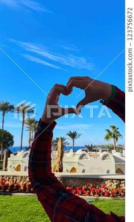 Love gesture against a tropical backdrop. 123756672