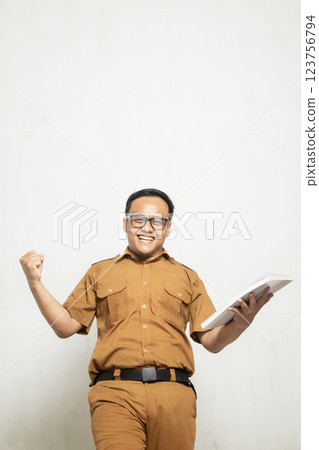 Indonesian Middle School Teacher is excited. The teacher is wearing old khaki and carrying a book, Indonesian Teacher Profile Concept isolated on white background 123756794