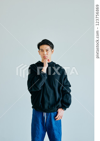 A young man in his twenties thinking with his chin in his hand A young man in his twenties thinking with his chin in his hand 123756869