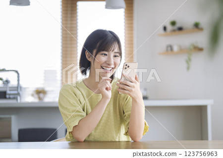 一位 30 多歲、微笑的女士正在操作智慧型手機 123756963