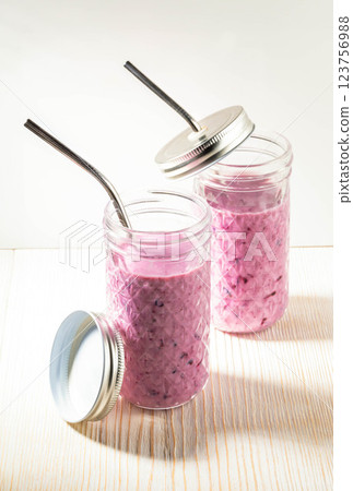 Refreshing healthy beverage Blueberry smoothie in two glasses with metallic drinking straws on white Refreshing healthy beverage Blueberry smoothie in two glasses with metallic drinking straws on white 123756988