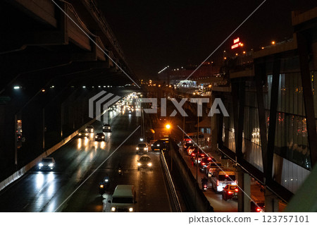 Vehicles navigate the busy highway, their headlights creating a stream of light against the dark backdrop. The urban environment hums with movement as city life thrives. Vehicles navigate the busy highway, their headlights creating a stream of light against the dark backdrop. The urban environment hums with movement as city life thrives. 123757101