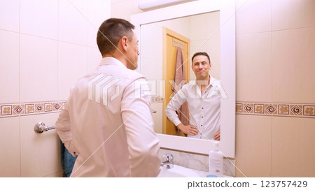 Businessman smiling at himself in bathroom, getting ready for work 123757429