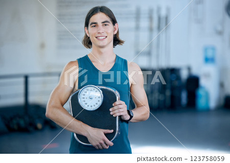 Fitness, exercise and weight scale with a sports man in the gym for training, workout or weightloss. Health, wellness and motivation with a male athlete in a club for exercising or staying active 123758059