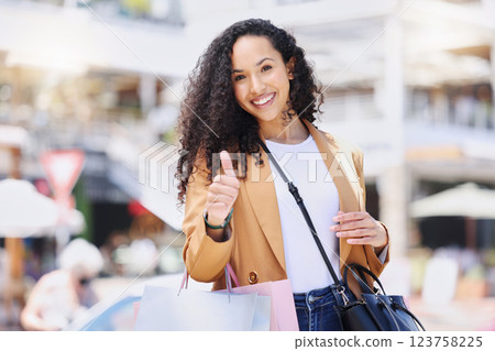Thumbs up, shopping and retail with a woman customer on the search for a sale, bargain or deal in an outdoor mall. Thank you, winner and hand with a young female in a store to shop, buy or purchase Thumbs up, shopping and retail with a woman customer on the search for a sale, bargain or deal in an outdoor mall. Thank you, winner and hand with a young female in a store to shop, buy or purchase 123758225