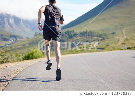 Running, fitness and exercise with a sports man and runner outdoor on a road in nature for training. Workout, marathon and health with a male athlete on a run for sport on a road in the mountains 123758383