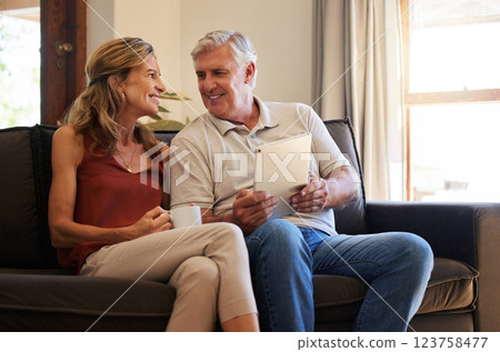 Tablet, social media and senior couple with smile for choice of movie on the web with coffee on sofa of their house. Elderly man and woman talking about show on subscription service on tech with tea 123758477