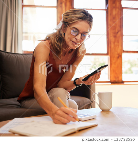 Senior woman, phone and writing calculation in book on sofa, web search or investment planning. Retirement, elderly female and 5g mobile, internet banking or budget and savings with coffee in house. Senior woman, phone and writing calculation in book on sofa, web search or investment planning. Retirement, elderly female and 5g mobile, internet banking or budget and savings with coffee in house. 123758550