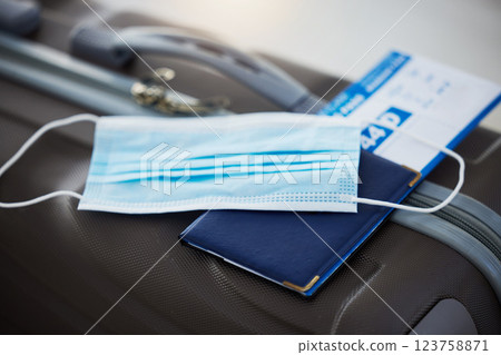 Covid mask, travel safety and airport documents for immigration, plane ticket holiday or vacation. Passport for airplane traveling with luggage and corona security and health safe measurements Covid mask, travel safety and airport documents for immigration, plane ticket holiday or vacation. Passport for airplane traveling with luggage and corona security and health safe measurements 123758871